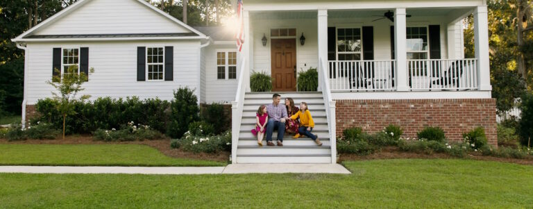 family sitting on steps in front of home